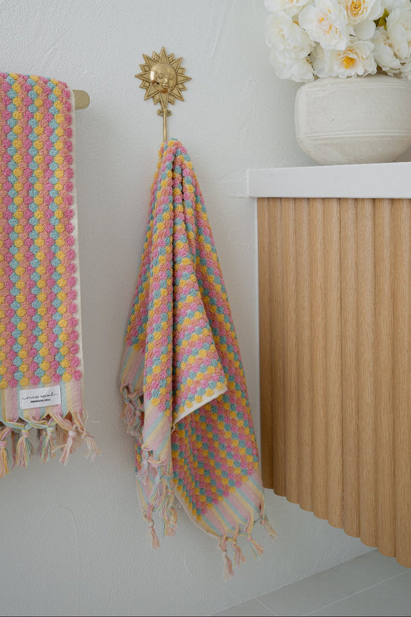 Bathroom with wooden vanity, colorful towel, and decorative flowers.