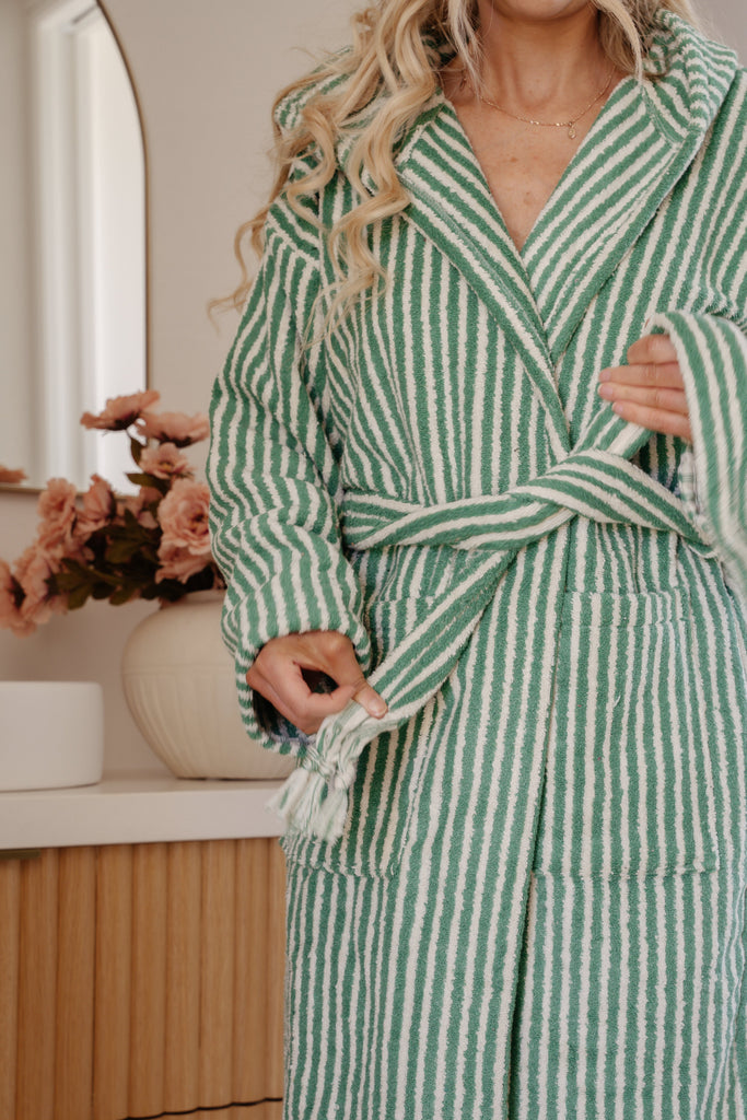 Person wearing a green and white striped robe in a bathroom setting.
