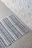 Eucalyptus Bathroom Set features a woven cotton bath mat with raised pompom stripes in white, grey, blue and green