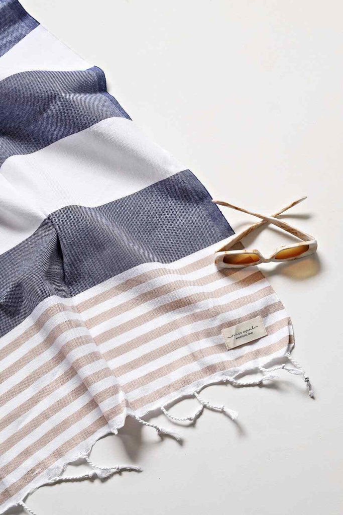 Navy and beige striped Flamenco Turkish towel with fringes and sunglasses