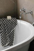 Black and white pompom Turkish cotton hooded baby towel on bathtub edge