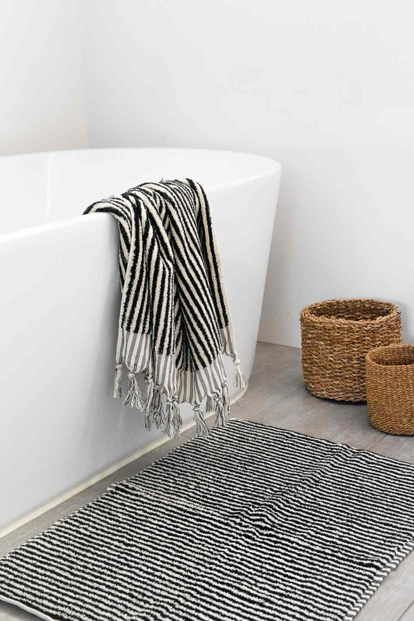 Turkish cotton black and white striped bath sheet hanging on bathtub with striped bath mat