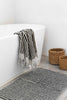 Turkish cotton black and white striped bath sheet hanging on bathtub with striped bath mat