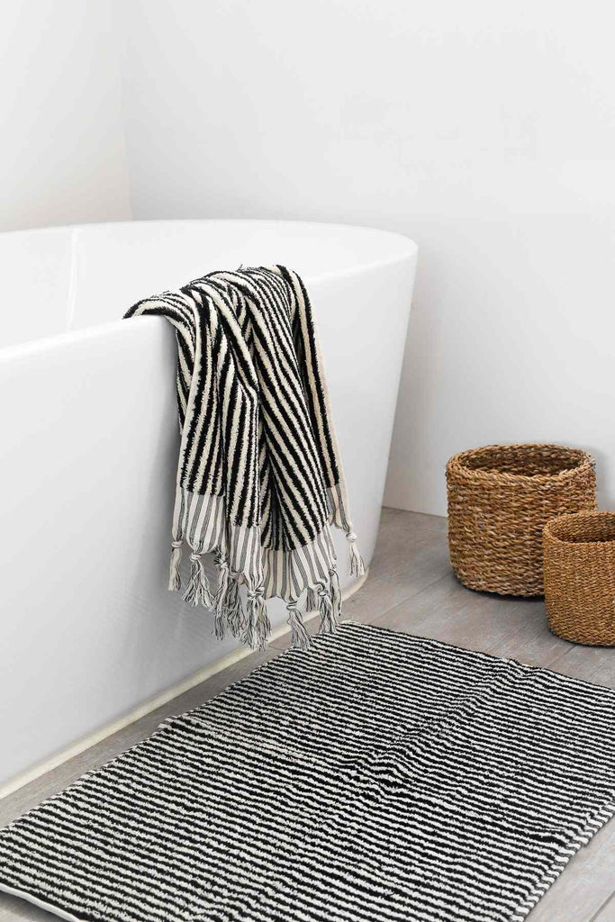 Turkish cotton black and white striped bath sheet hanging on bathtub with striped bath mat