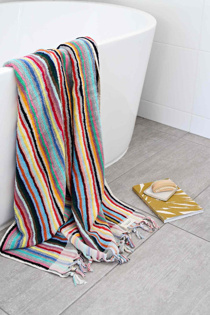 Turkish cotton bath towel multicolour stripes draped over bathtub